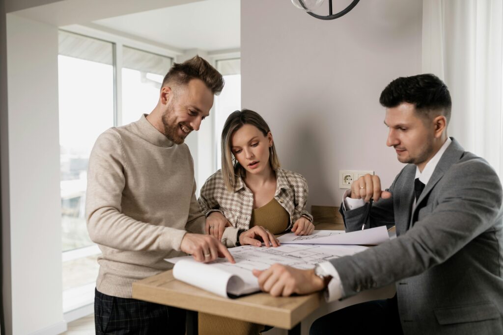 Three people reviewing design plans at a table